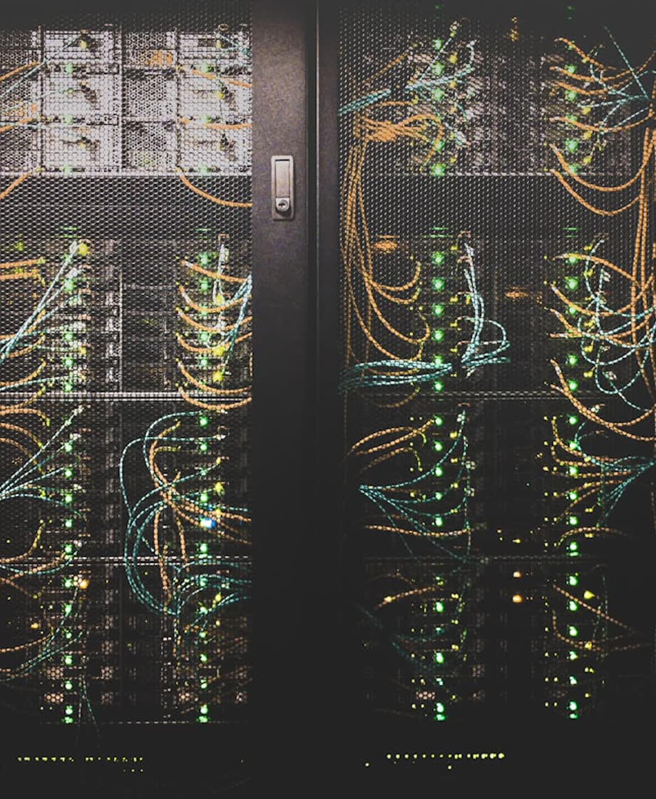 Rows of illuminated server racks laced with amber fiber cabling inside a data center